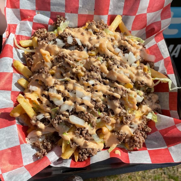 Rockin' Burgers' loaded fries with ground beef, cheese sauce, onions, and lettuce in a checkered basket.