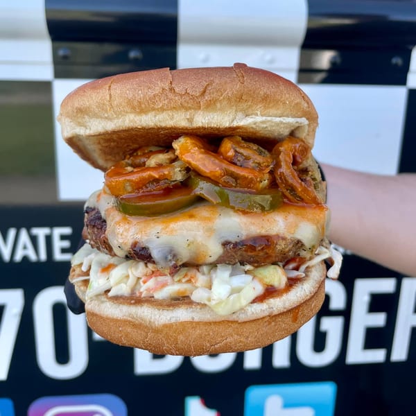 Rockin' Burgers' burger with melted cheese, coleslaw, jalapeños, and crispy onions on a bun.
